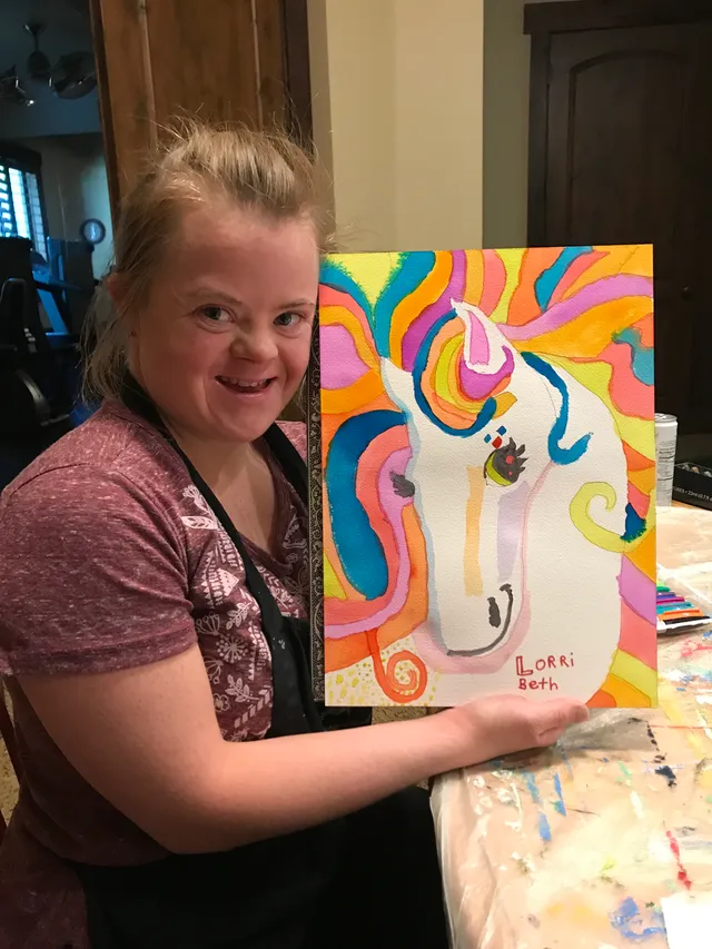 A Change 4 Love artist smiling with her colorful unicorn painting