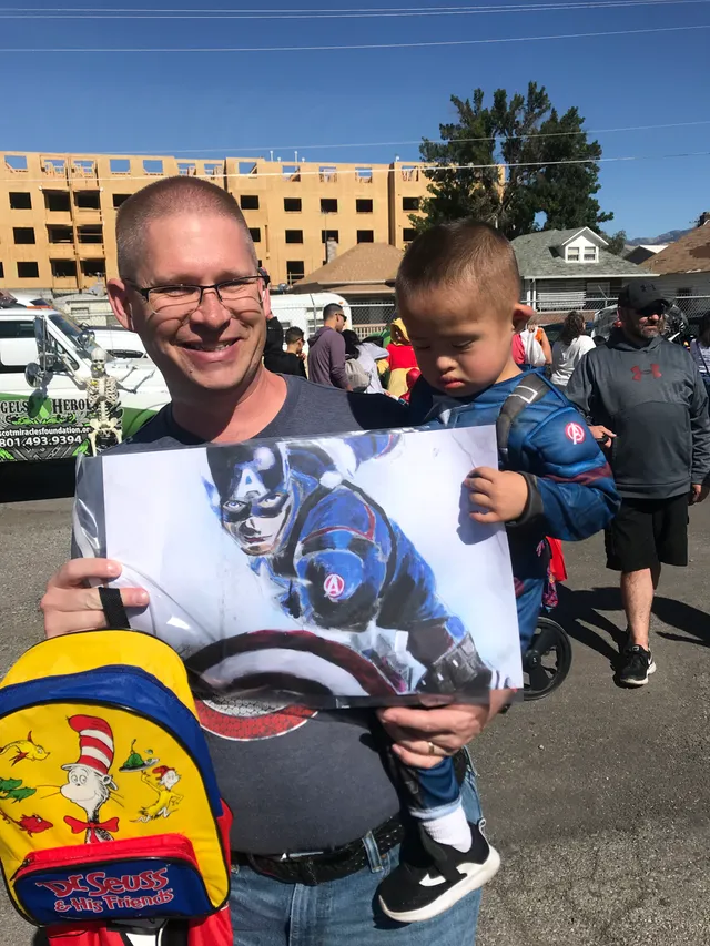 A Change 4 Love volunteer handing a superhero painting to a young boy
