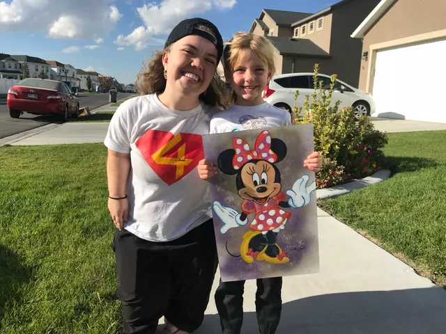 A child receiving a hand-painted Minnie Mouse painting